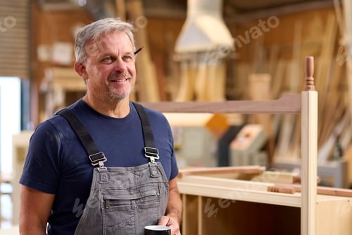 Preview: Portrait Of Mature Male Carpenter With Pencil Behind Ear And Hot Drink In Furniture Workshop