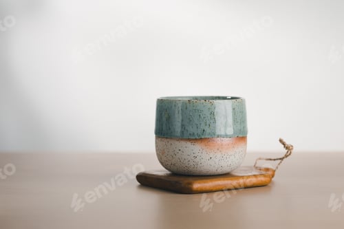 Preview: A dual-glazed ceramic cup rests on wood.