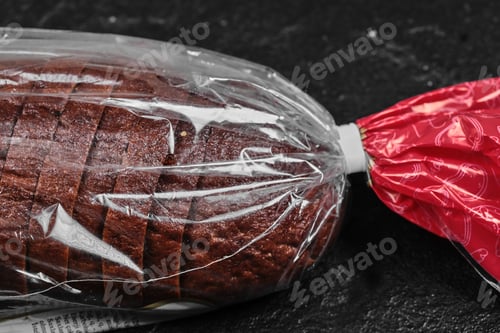 Preview: Sliced black rye bread in plastic bag on dark background
