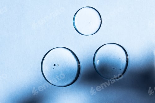 Preview: Liquid drops of cosmetic collagen and peptide on a blue background.