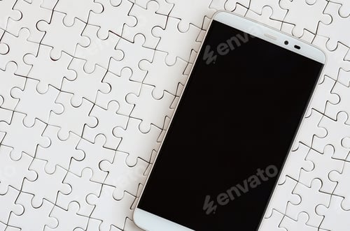 Preview: A modern big smartphone with a touch screen lies on a white jigsaw puzzle in an assembled state