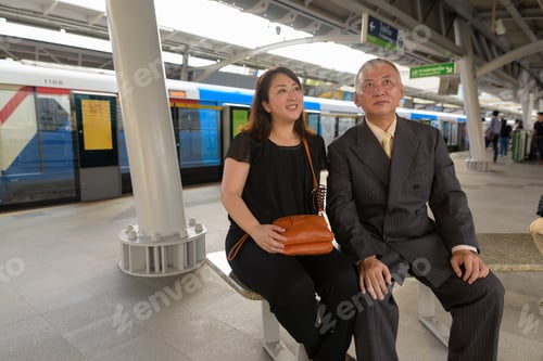 Preview: Mature Asian businessman and mature Asian woman exploring the city together