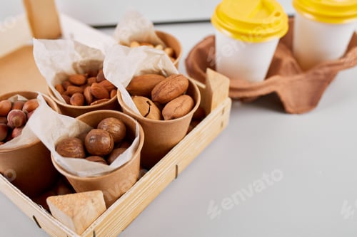 Preview: Two Takeaway Coffee Cups and a Variety of Nuts on a Bright Background