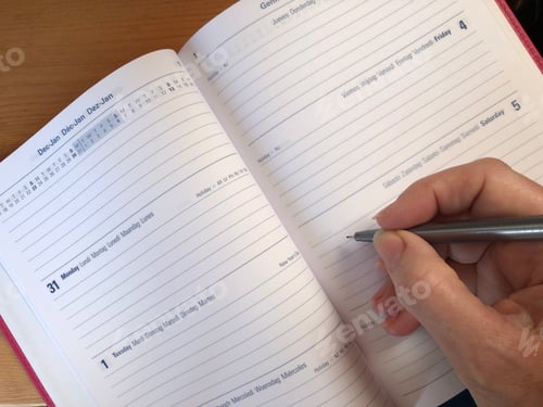 Preview: Week to view desk diary open to December January with a woman’s hand holding a pen about to write an