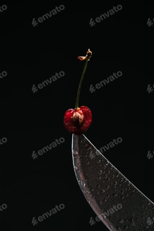 Preview: close-up view of half of ripe sweet cherry on knife isolated on black