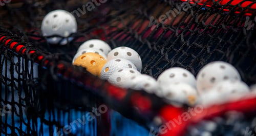 Preview: White and orange floorball balls on black net