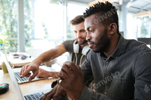 Preview: Concentrated young colleagues sitting in office coworking