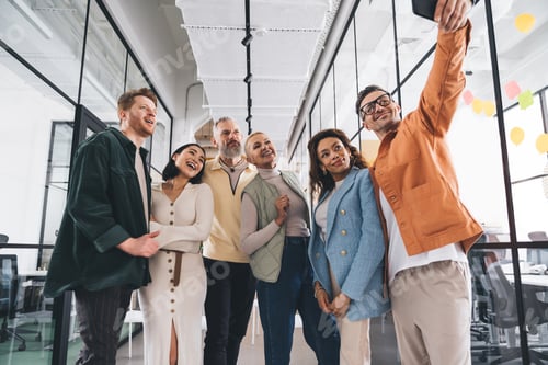 Preview: Group of multiethnic friends standing in modern office and taking selfie