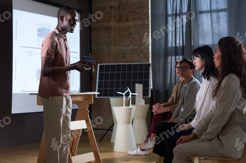 Preview: Businessman presenting solar battery to people