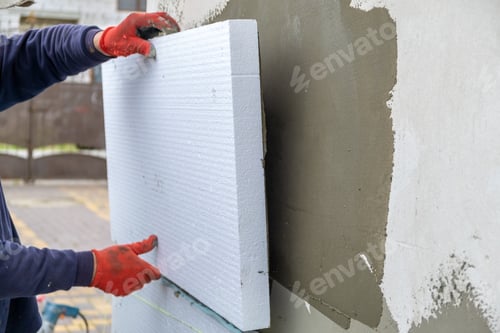 Preview: Construction worker installing styrofoam insulation sheets on house facade wall for thermal