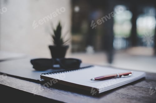 Preview: Small notepad with pen on wood background at cafe.