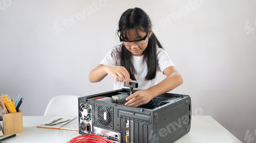 Preview: A little girl is repairing computer hardware at the white working table.