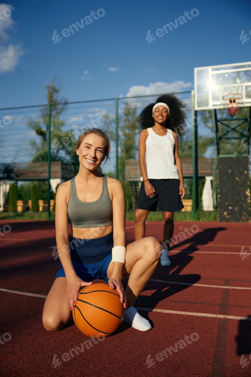 Preview: Cute multicultural female basketball player taking rest
