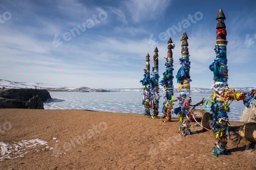 Preview: wooden pillars with colorful ribbons on seacoast at winter sea, Russia, Lake Baikal, march 2016