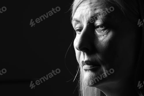 Preview: Senior woman crying on dark background, closeup. Black and white effect
