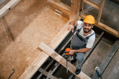 Preview: Saw in hands. Industrial worker in wooden warehouse