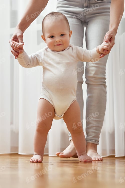 Preview: happy little baby girl learning to walk with mother help