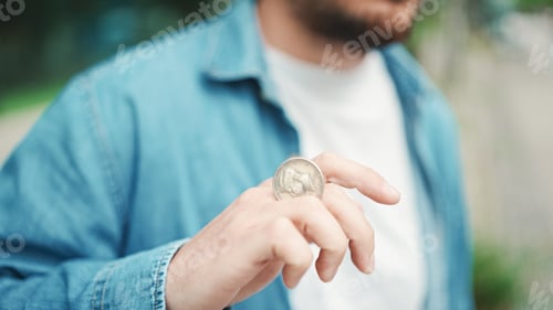 Preview: Closeup of hand moving coin - Tricks and sleight of hand, in background urban cityscape
