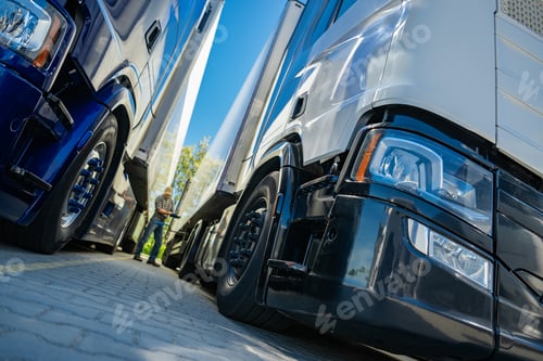 Preview: Trucks Parked Side by Side in a Freight Yard Under a Clear Daytime Sky