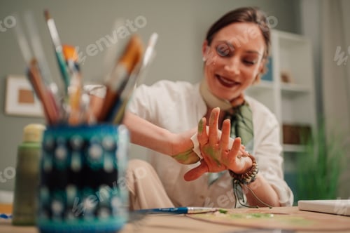 Preview: Female artist cleaning green paint from hands after creative work session