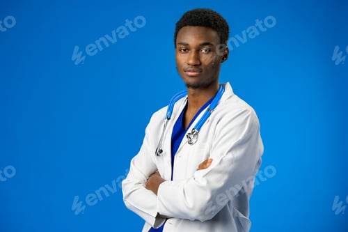 Preview: Confident black doctor posing over blue studio background