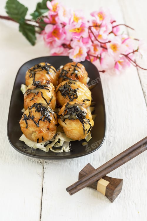 Preview: Close up of takoyaki on wooden table with chopsticks