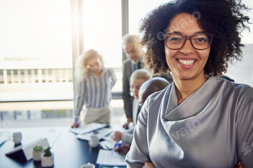 Preview: Young businesswoman smiling with colleagues working in the background