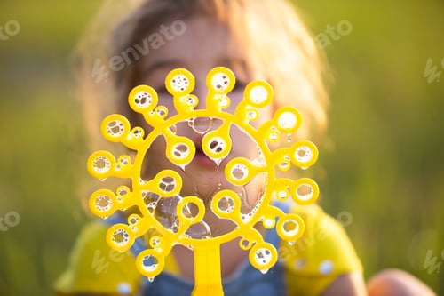 Preview: A girl in a denim jumpsuit blows soap bubbles in the summer in a field at sunset