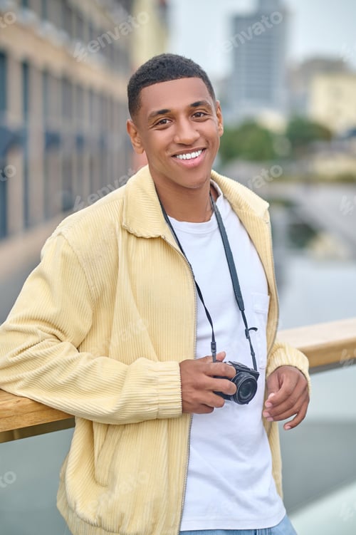 Preview: Dark-haired attractive photographer standing on a city background