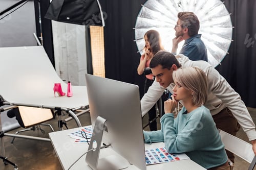 Preview: selective focus of coworkers looking at computer monitor in photo studio