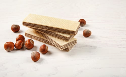 Preview: Delicious wafers with hazelnuts on white wooden background