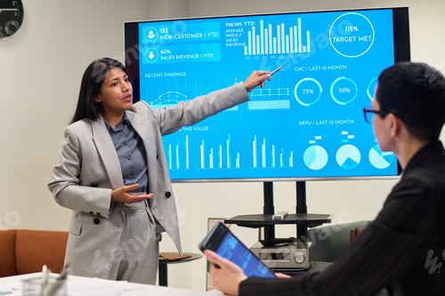 Preview: Young Adult Hispanic Woman Presenting Business Data to Caucasian Colleague