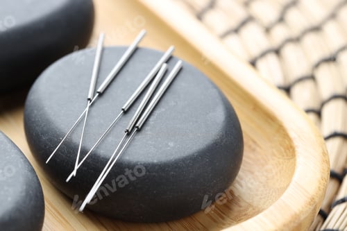 Preview: Acupuncture needles and spa stones on table, closeup
