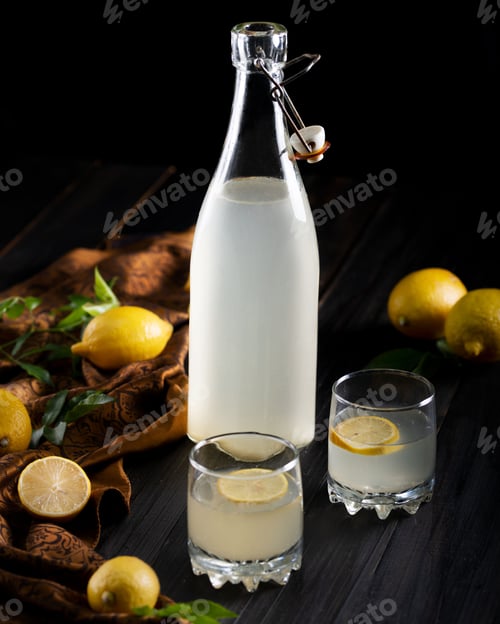 Preview: Vertical shot of a glass bottle filled with lemonade with fresh lemons on a table