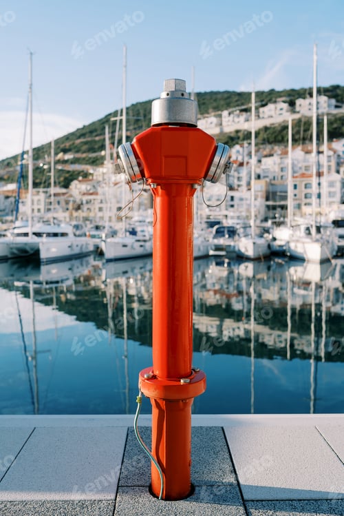 Preview: Red fire hydrant stands on a pier with moored yachts