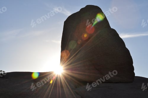 Preview: The lens flare of the sun as it rises behind the rocks or boulders at Joshua tree national park.