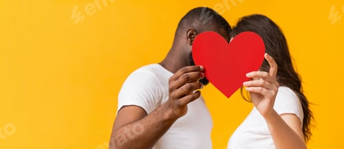 Preview: Romantic interracial couple kissing behind big red paper heart