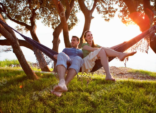 Preview: Couple lying in hammock at beach