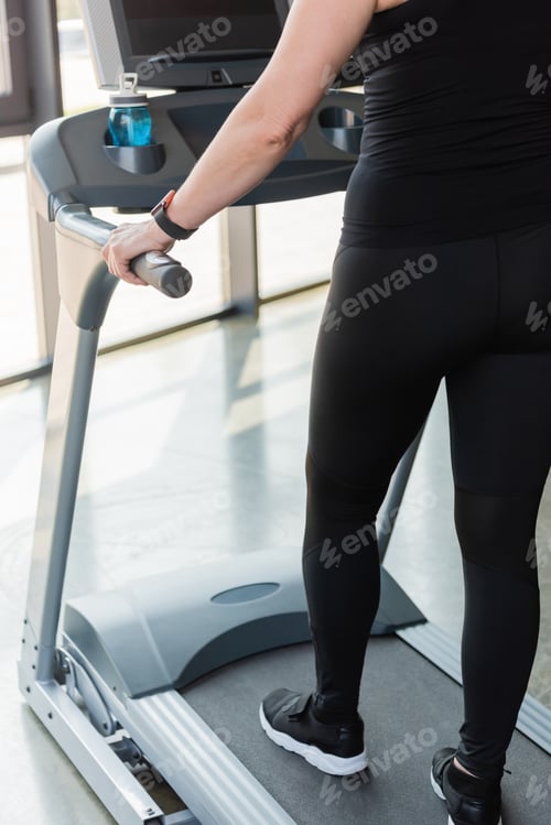 Preview: cropped view of senior woman in black leggings running on treadmill
