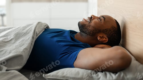 Preview: Happy Black Man Lying Holding Hands Behind Head In Bedroom