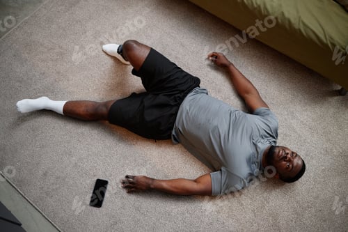 Preview: Young Adult Black Man Lying on Floor Indoors Experiencing House Arrest