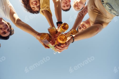 Preview: View from below of people that are cheering with beer bottles