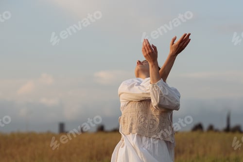 Preview: Young woman wearing white dress dancing outdoors against cloudy sky. Carefree female outdoors