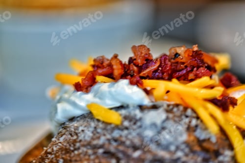 Preview: Baked potato filled with shredded cheddar cheese, sour cream, and sprinkled with crispy bacon bits
