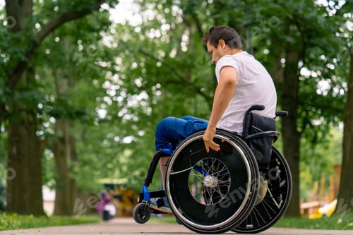 Preview: A man with a disability does wheelchair stunts in a city park against backdrop of trees