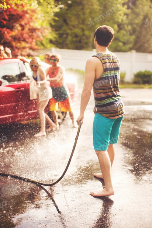 Preview: Teen sprays water hose during a summer car wash with friends laughing in the background.