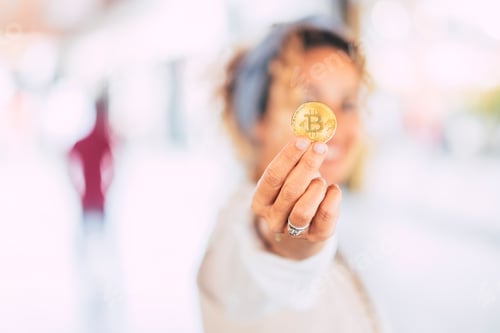 Preview: Cheerful modern caucasian woman in business world showing a gold bitcoin cryptocurrency