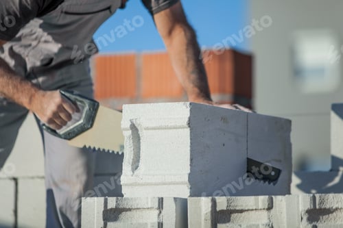 Preview: Shallow focus shot of a man builder sawing a gas-silicate block