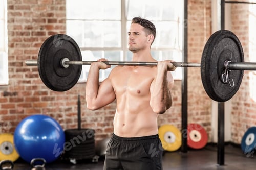 Preview: Muscular serious man doing weightlifting in crossfit gym