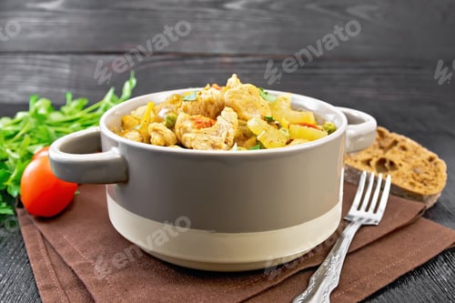 Preview: Chicken with vegetables and peas in saucepan on wooden board